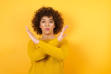 Young Arab businesswoman standing over yellow isolated background Rejection expression crossing arms doing negative sign, angry face