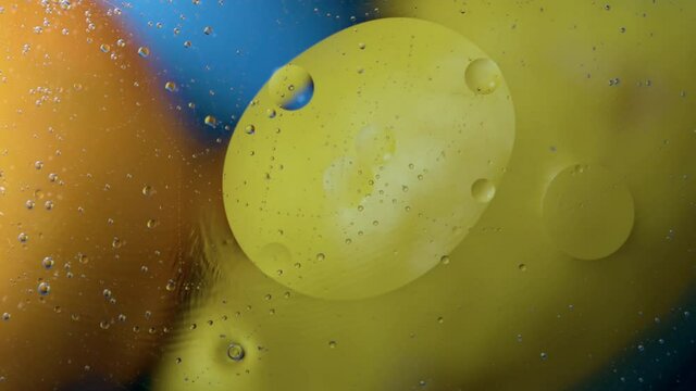 High quality abstract close-up 4k slow motion video of a bright colourful natural bacground with lemons and oranges giving orange blue and yellow colours with the water and oil bubbles moving around