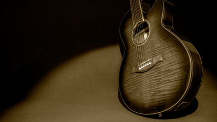 Retrato de una hermosa guitarra electroacústica de pie a la derecha sobre un fondo oscuro, iluminando sólo a la guitarra. Foto en escala de grises - Powered by Adobe