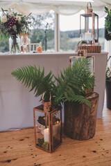 Wedding Top Table decor with candles, ferns, logs and lanterns in a marquee