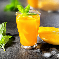 Glass of mango cocktail with mint on bar counter. Square image.