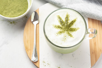 CBD or THC infused Matcha tea on white marble. Cannabis leaf tea. Warm vibes and relaxation. Healthy alternative to smoking or vaping. Medical or recreational use.
