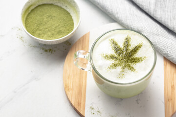 CBD or THC infused Matcha tea on white marble. Cannabis leaf tea. Warm vibes and relaxation. Healthy alternative to smoking or vaping. Medical or recreational use.