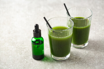 CBD oil dropper bottle and cannabis infused green health drink beverage for medical use. Cannabis drink infused with Indica sativa hybrid. Get well soon pain relief and nutrition.