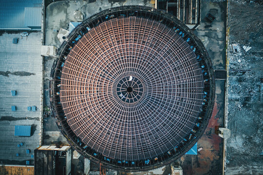Above round iron roof of unfinished nuclear power plant, circle metal construction, industrial building, aerial top view.