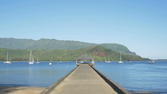 Long, slow pan from the Hanalei Bay pier to the Halalei Bay beach and nearby mountains, Kauaii, Hawaii.