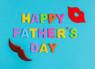 color inscription happy father's day.
colored inscription happy father's day and paper mustache and lips around the edges on a blue background, close-up