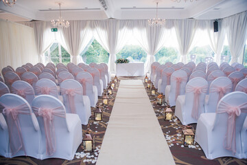 Room set up for wedding ceremony with white chairs, camdles and aisle runner