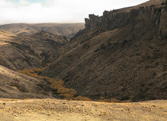 Rural landscape. Beautiful golden meadow and valley in autumn. Yellow grassland with rocky mountains and cliffs