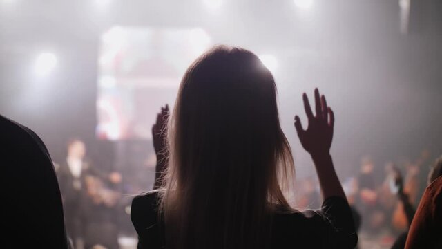 dancing girl raises her hands hair at a concert