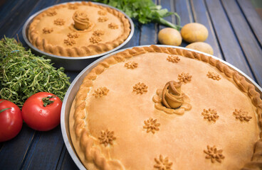 Two potato pies with edible decorations on top - greens and tomatoes on the sides