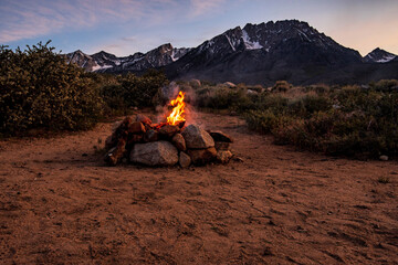 campfire in stone fire pit in desert at base of mountains with sunset sky - 355056037