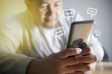 Asian man sending text message and sms with smartphone. Guy texting and using mobile phone late at night in dark. Communication or sexting concept. Chat icons
