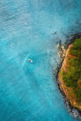 A beautiful Drone Shot of a white Sailing Yacht anchored in crystal clear Turquoise Water right next to the Tropical Island