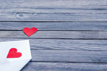 two red paper hearts in white envelope on gray wooden background, place for text