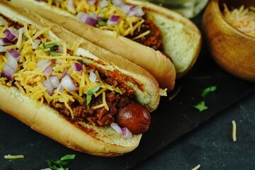 Homemade Chili dogs topped with cheddar cheese, selective focus
