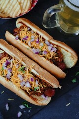 Homemade Chili dogs topped with cheddar cheese, selective focus