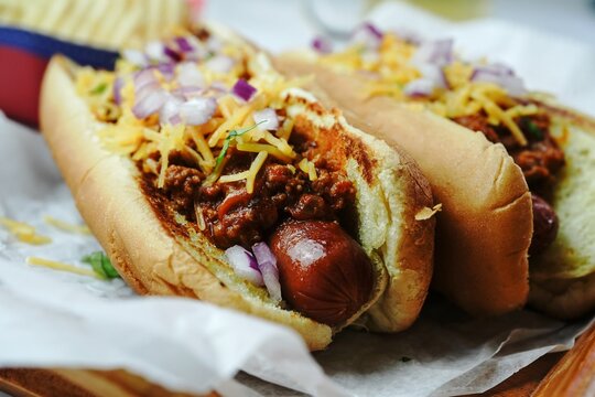 Homemade Chili dogs topped with cheddar cheese, selective focus
