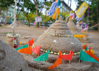  Tradition of carrying sand into the temple or monastery. Prayer flags on sand in Songkran day festival at Thailand.