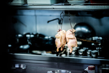 raw chicken hanging in kitchen for meal preparation
