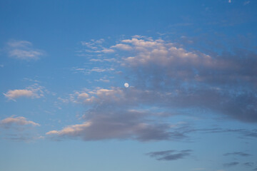 bright moon in blue sky and clouds at sunset