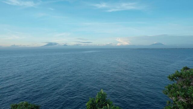 Marine landscape with blue clear water, clouds and volcanoes on the horizon