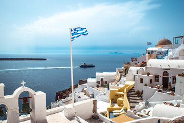 Greek flag flying over stunning landscape in Santorini.
