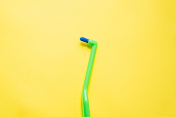 Green toothbrush with a single beam for braces on a yellow background