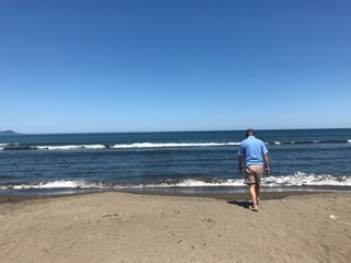 海に向かって歩く男性