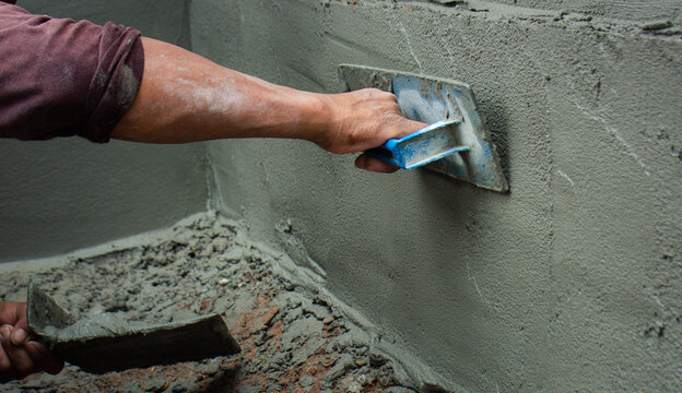 Construction workers in industrial buildings are plastering to build walls.