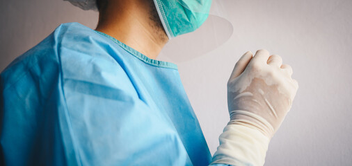 Close up of Doctor praying for God's blessings while wearing PPE suit for work at hospital in...