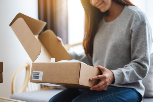 A Beautiful Young Asian Woman Receiving And Opening A Postal Parcel Box At Home For Delivery And Online Shopping Concept