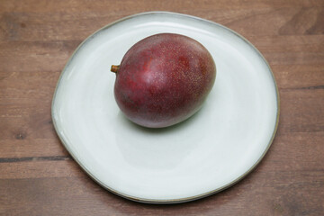 organic red ripe mango on a plate on a wooden table