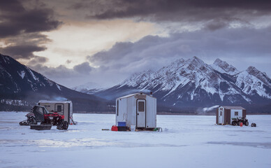 Ice fishing on Abraham Lake in Alberta with 3 ice shacks sitting on frozen lake with Rocky...