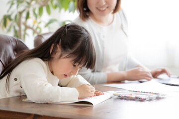 お絵描きをする女の子とテレワークをする母親