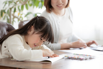 お絵描きをする女の子とテレワークをする母親