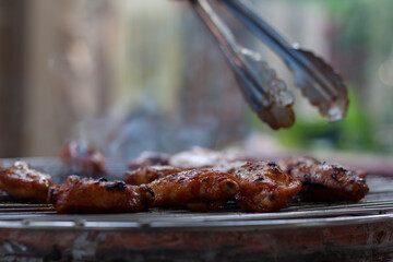 Grilled chicken wings on the grill with smoke lit floating on the vintage stove.