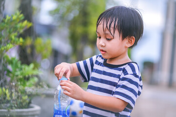 boy holding and opening bottle of drinking water in a park 