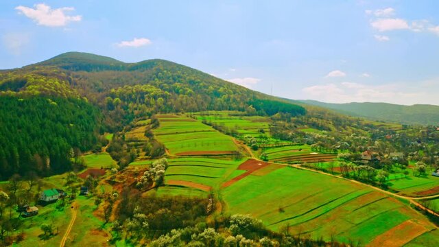 aerial view on rural landscape in spring on the background beautiful mountains with forest sunny daytime with blue sky