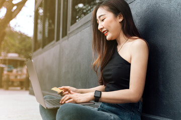 Young woman holding credit card and using laptop computer. Businesswoman working at home. Online shopping, e-commerce, internet banking, spending money, working from home concept