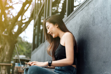 Young woman holding credit card and using laptop computer. Businesswoman working at home. Online shopping, e-commerce, internet banking, spending money, working from home concept