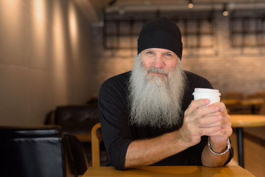 Mature handsome bearded hipster man sitting at the coffee shop
