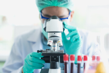 Professional Asian scientist or researcher man in work coat uniform using microscope to looking and...