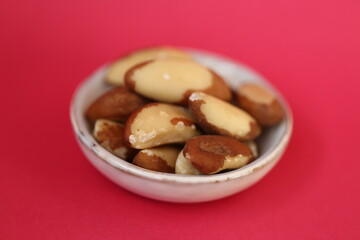 Brazil nut in a  gray cup  on a bright pink fuchsia background. Wholesome food and snack. Healthy fats ingredient. Vegetarian and vegan food.keto diet. 