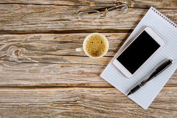 Notebook with blank pages on a smartphone pen on cup of coffee