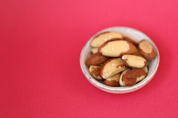Brazil nut in a ceramic gray cup  on a bright  fuchsia background. Wholesome food and snack. Healthy fats ingredient. Vegetarian and vegan food.keto diet. 