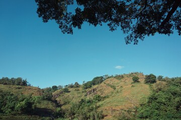 Landscape view of a hill and lake with clear blue skies.