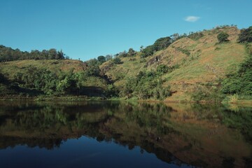 Landscape view of a hill and lake with clear blue skies.
