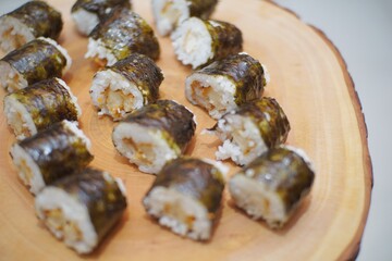 Close up of sushi on top of a wooden plate