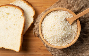 Crumbs and bread in a wooden bowl set against a wooden backdrop.